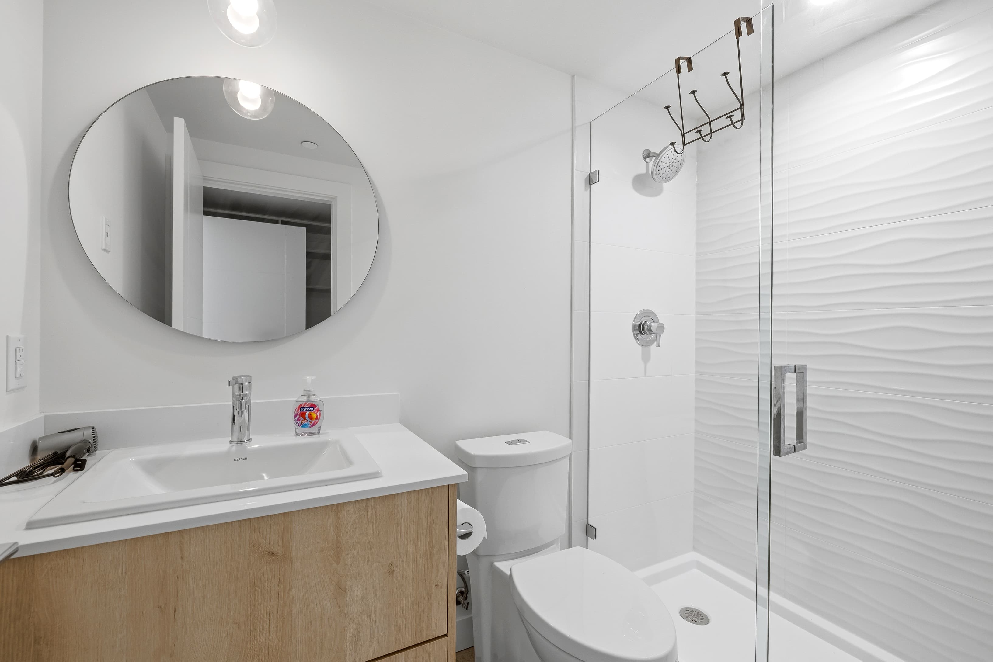 Bathroom with walk-in glass shower and round mirror